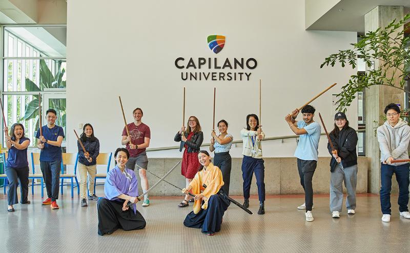 Students and staff posing together at the sword fighting workshop