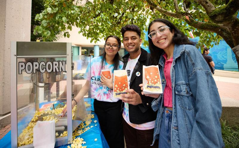 Student volunteers serving popcorn in Cedar Courtyard