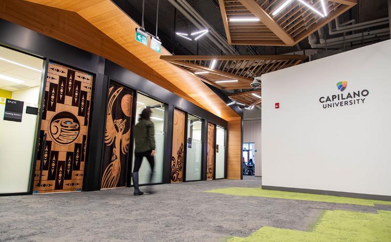 Student walking in front of Indigenous doors at CapU Lonsdale