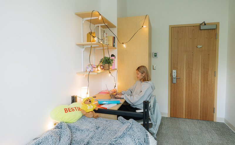 A student sitting at their desk in student housing