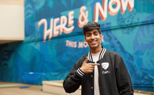 Student standing in front of mural