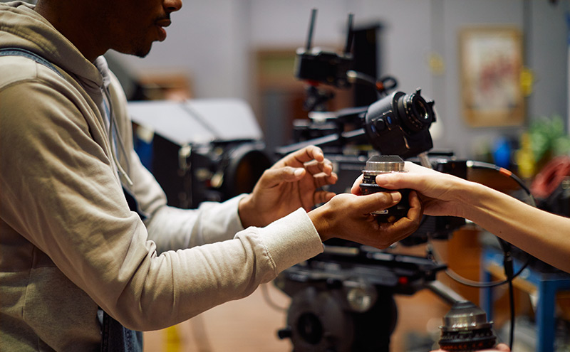 Film students handing off a camera lens.