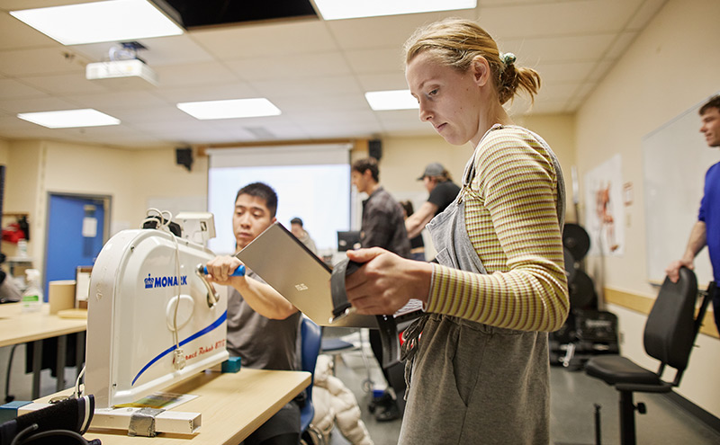 CapU kinesiology student running a fitness test with a stopwatch and iPad.