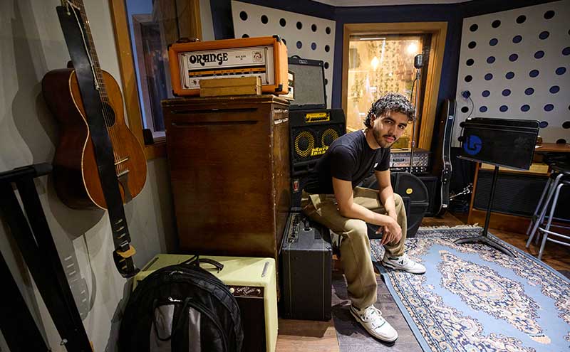 CapU student Joel Miguel Norena Cardenas sitting with equipment at Blue Light Studio.