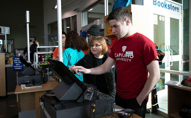 CapU Education & Employment Access Certificate student working at a retail sales till.