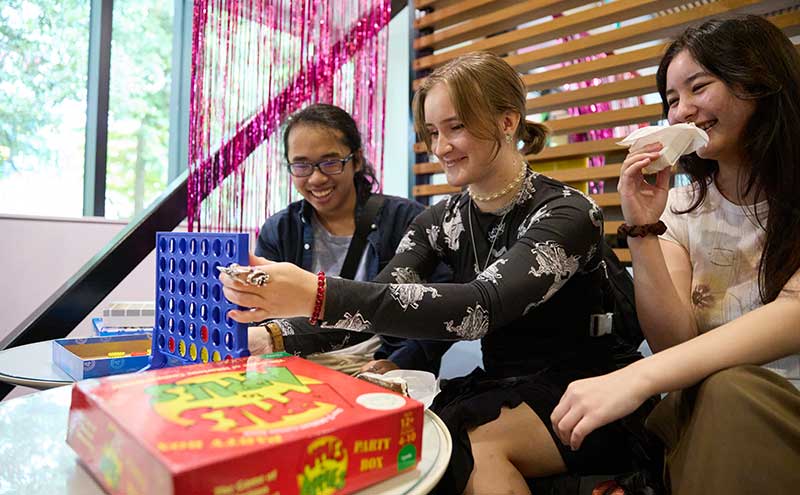 Three students playing Connect Four at Orientation.