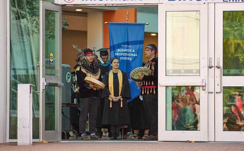 Student with Indigenous performers at Convocation